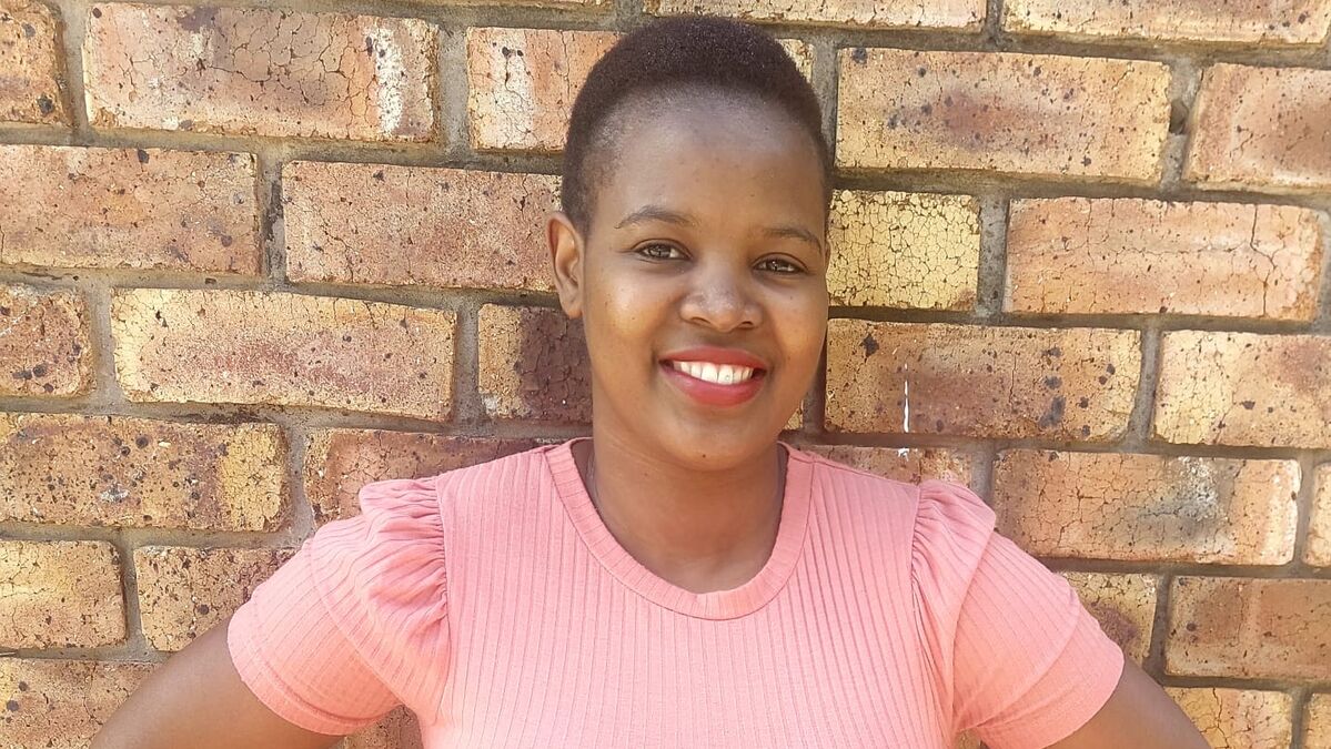 Ndivhuwo smiles in front of brick wall