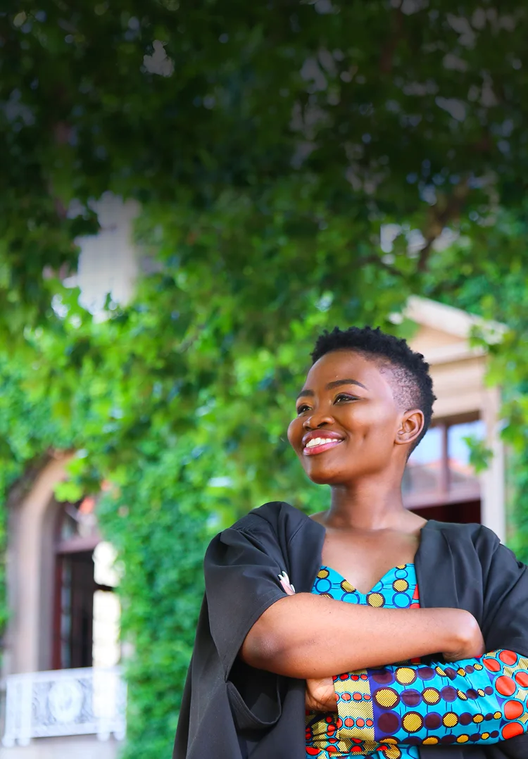 A Dell Young Leader graduate stands in front of a university building.